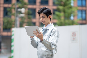 タブレットを持つ作業着の男性
