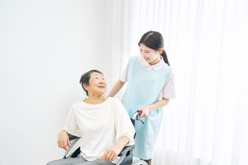 Obraz premium 車椅子に乗った高齢者と話す介護士