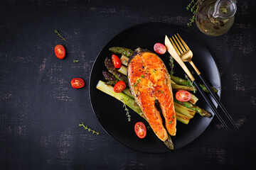 Roasted salmon garnished with asparagus and tomatoes with herbs. Ketogenic lunch. Keto diet. Top view, above