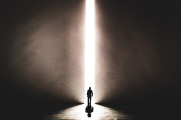The silhouette of a man walking towards a bright light in the opened huge wall. A light in the end of a tunnel. The concept of success, freedom of choice, open mind, meditation. - 553152641