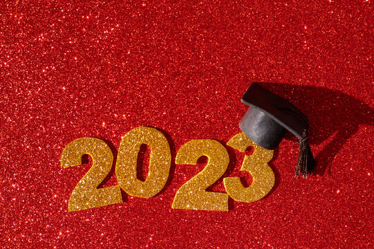 Class of 2023 concept. Numbers 2023 with black graduated cap on glitter red background