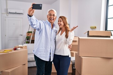 Middle age man and woman couple make selfie by the smartphone at new home