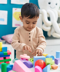 Adorable hispanic toddler playing with construction blocks standing at home