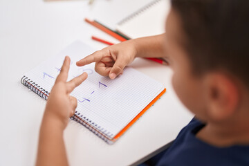 Adorable hispanic toddler doing mathematics exercise counting with fingers at classroom