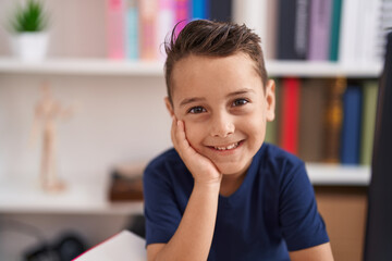Adorable hispanic toddler smiling confident sitting on table at library school