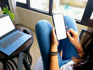 computer, blank screen phone mockup image with white background for advertising, woman's hand using laptop and mobile phone on table in cafe.mockup