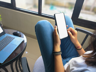 computer, blank screen phone mockup image with white background for advertising, woman's hand using laptop and mobile phone on table in cafe.mockup