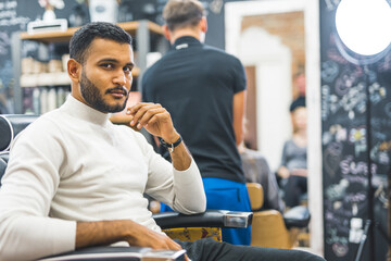 Young man sitting in a chair at barbershop. High quality photo