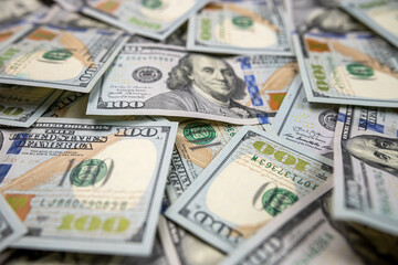 close-up stacks of hundred dollar bills isolated on dark background.