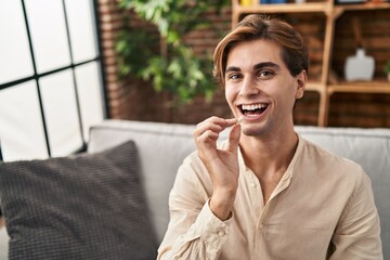 Young caucasian man holding bubble gum sitting on sofa at home