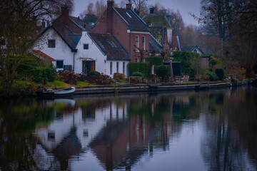 cosy looking houses in Oud Zuilen netherlands. Buildings and a boat reflect in the river Vecht near Utrecht on a cold winter day