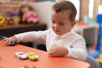 Adorable toddler playing with car toy sitting on table at kindergarten