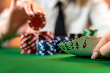 woman's hand on a pile of poker chips at a round poker table.