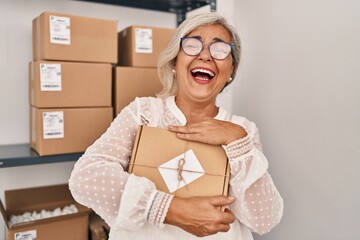 Middle age woman ecommerce business worker holding package order at office