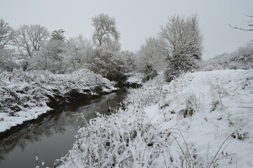 A cold, dull snow covered morning in Horley, Surrey by the River Mole on 12 Dec 2022. 