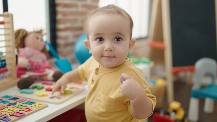 Adorable hispanic baby playing with maths puzzle game standing at kindergarten