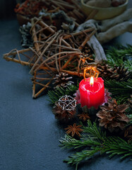 Candle, amulet deer, pentacle star, cones, fir branches on dark abstract background. Witchcraft...