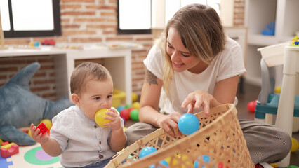 Mother and son sucking ball sitting on floor at kindergarten