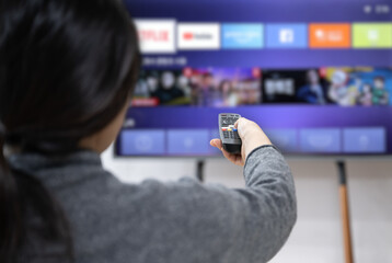 A woman experiences OTT service using a smart TV at home