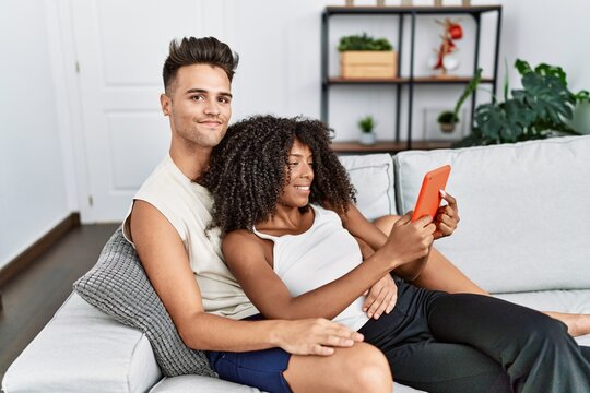 Man and woman couple using touchpad hugging each other at home