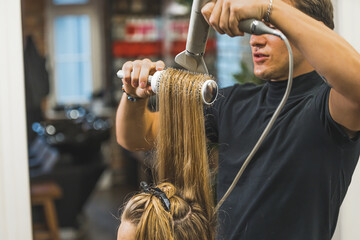 Male hairdresser blowdrying long hair of a woman. High quality photo