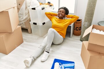 African american woman sitting on floor relaxed with hands on head at new home