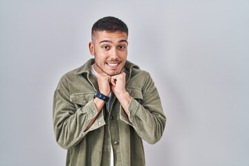 Young hispanic man standing over isolated background laughing nervous and excited with hands on...