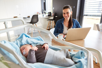 Smiling mother working from home and sleeping baby