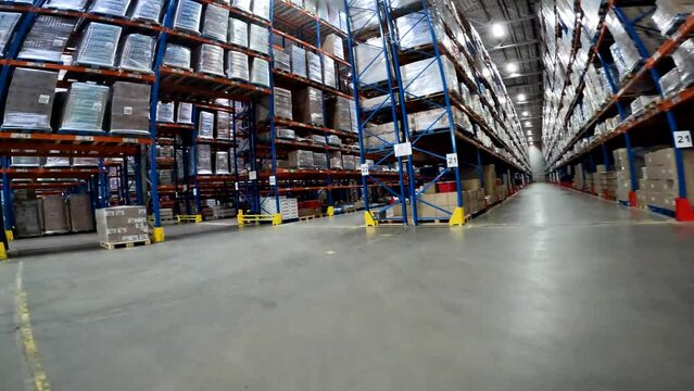A forklift is driving through a large warehouse. Moving through a modern warehouse. Large modern warehouse in the factory
