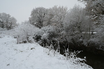 A cold, dull snow covered morning in Horley, Surrey by the River Mole on 12 Dec 2022. 