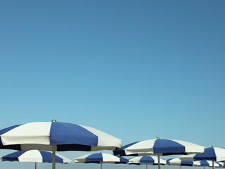 Fototapeta na wymiar Many blue and white beach umbrellas near sea