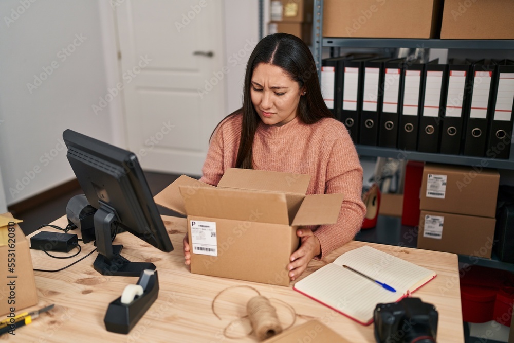 Canvas Prints Young latin woman working at small business ecommerce clueless and confused expression. doubt concept.