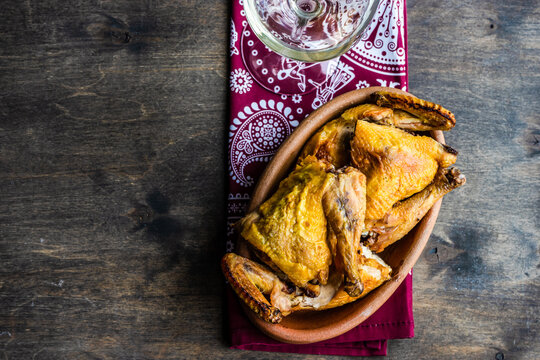 Dish with chicken tabaka and a glass of white wine on a table with a traditional tablecloth