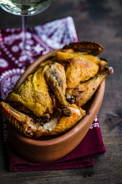 Dish with chicken tabaka and a glass of white wine on a table with a traditional tablecloth
