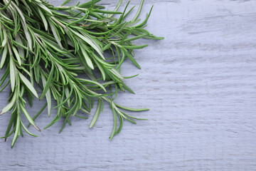 Fototapeta premium Sprigs of fresh rosemary on wooden table, above view. Space for text