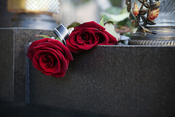 Red roses and grave light on grey granite tombstone outdoors, space for text. Funeral ceremony - obrazy, fototapety, plakaty