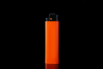 Orange plastic cigarette lighter on black background, closeup