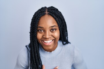 African american woman standing over blue background smiling and laughing hard out loud because funny crazy joke with hands on body.