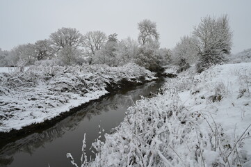 A cold, dull snow covered morning in Horley, Surrey by the River Mole on 12 Dec 2022. 