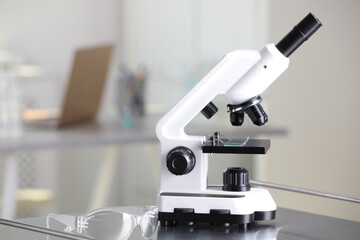 Modern medical microscope on metal table in laboratory, space for text