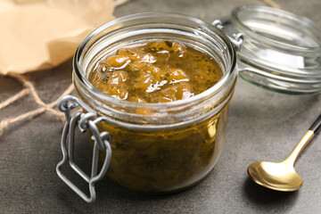 Jar of delicious gooseberry jam on grey table, closeup