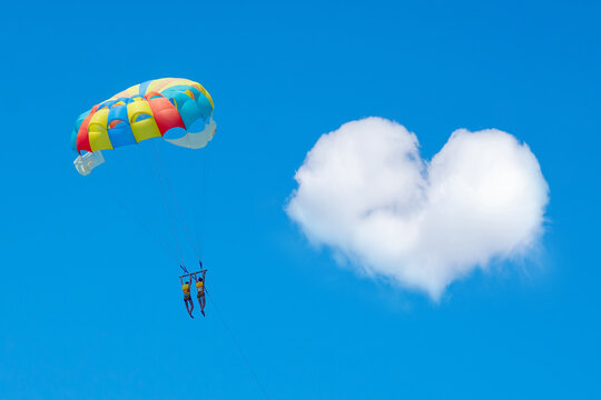 two people parachute to a heart-shaped cloud
