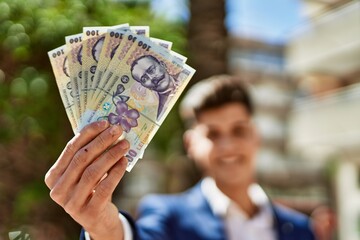 Young man wearing suit holding romania lei banknotes at street