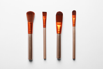 Different makeup brushes on white background, flat lay