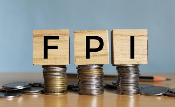 Concept of FPI or foreign portfolio investment on India in wooden block letters on stack of coins. 