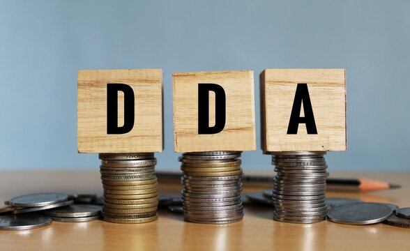 DDA (Demand Deposit Account) - words on a green sheet on the background of a graph, pencils and coins. Business concept