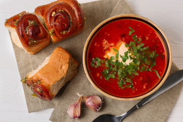Delicious borsch served with pampushky on white wooden table, top view. Traditional Ukrainian cuisine