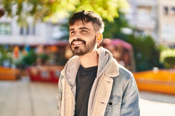 Young hispanic man smiling confident looking to the side at park