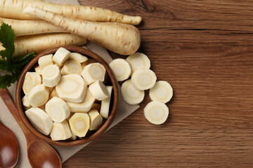Flat lay composition with whole and cut fresh ripe parsnips on wooden table. Space for text
