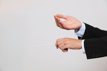 Professional conductor with baton on light grey background, closeup. Space for text